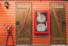 Brandslang in het rode kabinet hangen op oranje houten muur Het materiaaldoos van de brandnoodsituatie voor veiligheid en veiligh royalty-vrije stock fotografie Brandslang in het rode kabinet hangen op oranje houten muur Het materiaaldoos van de brandnoodsituatie voor veiligheid en veiligh royalty-vrije stock fotografie