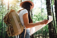 Brave hipster girl traveling alone and looking around in forest on outdoors wearing treveler backpack and hold location map in han Stock Photography Brave hipster girl traveling alone and looking around in forest on outdoors wearing treveler backpack and hold location map in han Stock Photography