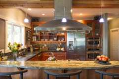 Breakfast bar in contemporary upscale home kitchen interior with granite countertops, vent hood and accent lighting