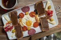 Breakfast with fried egg, rye bread, pomegranate, carob paste, cheeses, olives, dry salami, tomatoes and tea royalty free stock images Breakfast with fried egg, rye bread, pomegranate, carob paste, cheeses, olives, dry salami, tomatoes and tea royalty free stock images