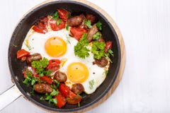 Fried eggs with sausages and vegetables in a frying pan stock image Fried eggs with sausages and vegetables in a frying pan stock image