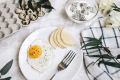 Breakfast Of Fried Egg And Pear On A White Plate With A Fork. In A Glass Bowl, Yogurt And A Dragon Fruit, Next To A Tray Of Quail Breakfast Of Fried Egg And Pear On A White Plate With A Fork. In A Glass Bowl, Yogurt And A Dragon Fruit, Next To A Tray Of Quail