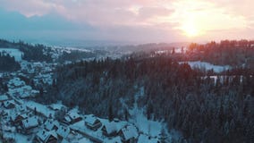Breathtaking sunrise over the evergreen forest during snow fall and small town Zakopane, Poland