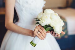 Bridal white peony bouquet in bride`s hands, shot in the bedroom Stock Images Bridal white peony bouquet in bride`s hands, shot in the bedroom Stock Images