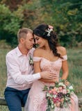 The bride and groom are sitting on a wooden fence. The guy and the girl are gently hugging each other. Wedding in pink royalty free stock photo The bride and groom are sitting on a wooden fence. The guy and the girl are gently hugging each other. Wedding in pink royalty free stock photo
