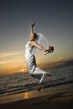 Bride jumping on beach.