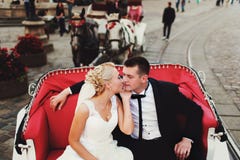 Bride kisses groom tenderly sitting in a red carriage stock photos Bride kisses groom tenderly sitting in a red carriage stock photos