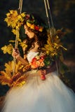 Bride looks stunning sitting on the swing full of autumn flowers royalty free stock photo Bride looks stunning sitting on the swing full of autumn flowers royalty free stock photo