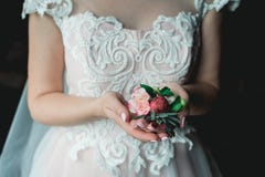 Bride in a luxurious wedding dress holding a wedding buttonhole made of roses Royalty Free Stock Image Bride in a luxurious wedding dress holding a wedding buttonhole made of roses Royalty Free Stock Image