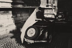 Bride's veil hangs down while she sits with groom on a retro car stock photography Bride's veil hangs down while she sits with groom on a retro car stock photography
