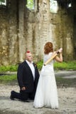 Bride is trying to hit an apple from a groom head with a baseball bat.