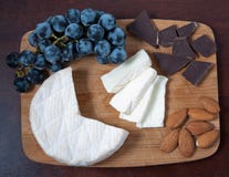 Brie, druiven, chocolade en amandelen op een houten raad royalty-vrije stock foto's Brie, druiven, chocolade en amandelen op een houten raad royalty-vrije stock foto's