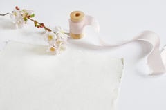 Bright feminine spring stationery mockup scene with a handmade paper greeting card, spool of silk ribbon and pink cherry Royalty Free Stock Image Bright feminine spring stationery mockup scene with a handmade paper greeting card, spool of silk ribbon and pink cherry Royalty Free Stock Image