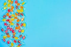 Bright multicolored candies in wrappers of transparent mica, sweets on blue background, colorful candy scattered, top stock photo Bright multicolored candies in wrappers of transparent mica, sweets on blue background, colorful candy scattered, top stock photo
