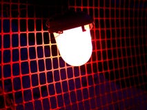 Bright red construction lamp in the mesh background. stock photo Bright red construction lamp in the mesh background. stock photo