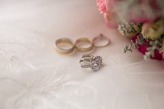 Brincos do casamento do ouro branco com as pedras preciosas que encontram-se perto das flores e dos anéis imagens de stock royalty free Brincos do casamento do ouro branco com as pedras preciosas que encontram-se perto das flores e dos anéis imagens de stock royalty free