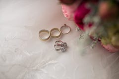 Brincos do casamento do ouro branco com as pedras preciosas que encontram-se perto das flores e dos anéis Joia nupcial e close-up foto de stock Brincos do casamento do ouro branco com as pedras preciosas que encontram-se perto das flores e dos anéis Joia nupcial e close-up foto de stock