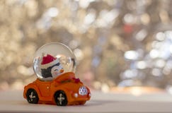 Brinquedo de vidro do Natal, boneco de neve em um carro vermelho em um fundo borrado prateado foto de stock Brinquedo de vidro do Natal, boneco de neve em um carro vermelho em um fundo borrado prateado foto de stock