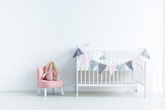 Brinquedo do luxuoso na cadeira cor-de-rosa ao lado da ucha branca no bedro branco do ` s do bebê imagens de stock royalty free Brinquedo do luxuoso na cadeira cor-de-rosa ao lado da ucha branca no bedro branco do ` s do bebê imagens de stock royalty free