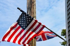 Britse en Amerikaanse vlaggen die van een doorstaan dakspaanhuis vliegen voor een elektrische pool en een blauwe bewolkte hemel royalty-vrije stock afbeelding Britse en Amerikaanse vlaggen die van een doorstaan dakspaanhuis vliegen voor een elektrische pool en een blauwe bewolkte hemel royalty-vrije stock afbeelding