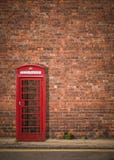 Británicos Phonebox contra la pared de ladrillo roja Imágenes de archivo libres de regalías Británicos Phonebox contra la pared de ladrillo roja Imágenes de archivo libres de regalías