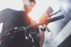 Brodaty mięśniowy tatuujący modniś w okularach przeciwsłonecznych używać smartphone po jechać elektryczną hulajnogą w mieście fotografia royalty free Brodaty mięśniowy tatuujący modniś w okularach przeciwsłonecznych używać smartphone po jechać elektryczną hulajnogą w mieście fotografia royalty free