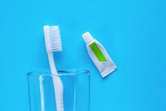 Brosse à dents blanche dans le verre transparent avec la pâte dentifrice utilisée pour nettoyer les dents sur le fond bleu image libre de droits Brosse à dents blanche dans le verre transparent avec la pâte dentifrice utilisée pour nettoyer les dents sur le fond bleu image libre de droits
