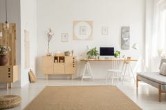 Brown carpet between pouf and grey sofa in white home office int