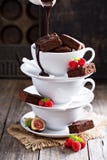 Brownies στα συσσωρευμένα φλυτζάνια καφέ με τη σάλτσα σοκολάτας Στοκ Φωτογραφίες Brownies στα συσσωρευμένα φλυτζάνια καφέ με τη σάλτσα σοκολάτας Στοκ Φωτογραφίες