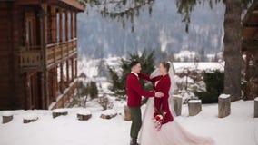 Brudgummen kommer till bruden, kramar och kysser henne i snöig bergby på skidar semesterorten Romantiska brölloppar, i stuckit Brudgummen kommer till bruden, kramar och kysser henne i snöig bergby på skidar semesterorten Romantiska brölloppar, i stuckit