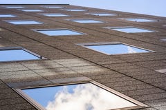 Brun kontorsbyggnadyttersida med fyrkantiga spegelmodeller som reflekterar himlen och molnen som skjutas från botten fotografering för bildbyråer Brun kontorsbyggnadyttersida med fyrkantiga spegelmodeller som reflekterar himlen och molnen som skjutas från botten fotografering för bildbyråer