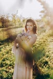 Brunetki dziewczyna trzyma bukiet dzicy kwiaty w jabłczanym sadzie fotografia stock Brunetki dziewczyna trzyma bukiet dzicy kwiaty w jabłczanym sadzie fotografia stock