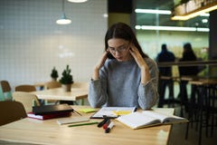 Brunetki dziewczyna w szkłach wykonuje dziennego pracy obsiadanie w sklep z kawą podczas gdy czekający kolega z klasy spotyka po zdjęcie stock Brunetki dziewczyna w szkłach wykonuje dziennego pracy obsiadanie w sklep z kawą podczas gdy czekający kolega z klasy spotyka po zdjęcie stock