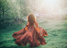 A brunette girl with wavy, thick hair runs to the meeting of the sun. Photo from the back, without a face. She has a l royalty free stock image A brunette girl with wavy, thick hair runs to the meeting of the sun. Photo from the back, without a face. She has a l royalty free stock image