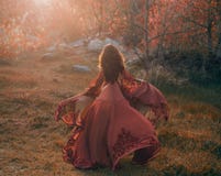 A brunette girl with wavy, thick hair runs to the meeting of the sun. Photo from the back, without a face. The princess royalty free stock photography A brunette girl with wavy, thick hair runs to the meeting of the sun. Photo from the back, without a face. The princess royalty free stock photography