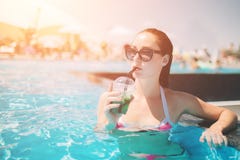 Brunettflicka med coctailar som kopplar av i simbassäng Sexig kvinna i bikini som tycker om sommarsolen och garvar under royaltyfria bilder Brunettflicka med coctailar som kopplar av i simbassäng Sexig kvinna i bikini som tycker om sommarsolen och garvar under royaltyfria bilder