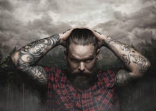 Brutal bearded male with tattooed arm looks down. stock photography Brutal bearded male with tattooed arm looks down. stock photography