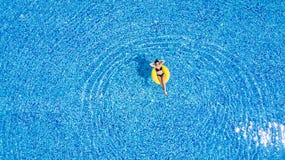 Bräunen in einem Pool Frau entspannen sich im Pool am sonnigen Tag im gelben aufblasbaren Ring stockbild Bräunen in einem Pool Frau entspannen sich im Pool am sonnigen Tag im gelben aufblasbaren Ring stockbild