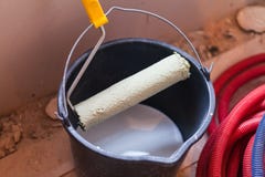 A bucket with white paint and a roller on an apartment is under construction Stock Photo A bucket with white paint and a roller on an apartment is under construction Stock Photo