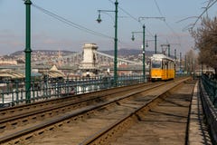 Budapest, Ungheria, il 22 marzo 2018: Tram giallo nell'inverno in anticipo con il cielo nuvoloso Il tram numero 2 è famoso per es immagini stock libere da diritti Budapest, Ungheria, il 22 marzo 2018: Tram giallo nell'inverno in anticipo con il cielo nuvoloso Il tram numero 2 è famoso per es immagini stock libere da diritti