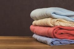 Bunch of knitted warm sweaters with different knitting patterns folded in stack on brown wooden table royalty free stock image Bunch of knitted warm sweaters with different knitting patterns folded in stack on brown wooden table royalty free stock image
