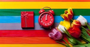 Bunch of tulips, red clock and gift lying on the table Royalty Free Stock Image Bunch of tulips, red clock and gift lying on the table Royalty Free Stock Image