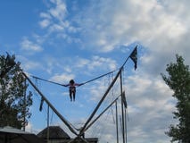 Bungee som hoppar på en karneval med flickan upp höjdpunkt mot en molnig himmel arkivbild Bungee som hoppar på en karneval med flickan upp höjdpunkt mot en molnig himmel arkivbild
