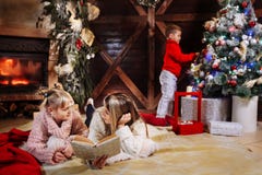 Buon Natale e buon anno Bella famiglia nell'interno di natale Madre giovane graziosa che legge un libro a lei immagini stock libere da diritti Buon Natale e buon anno Bella famiglia nell'interno di natale Madre giovane graziosa che legge un libro a lei immagini stock libere da diritti