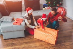 Buon Natale e buon anno Immagine di piccolo assistente che tiene pezzo di carta per il regalo Lei sorriso dei genitori giovane immagini stock Buon Natale e buon anno Immagine di piccolo assistente che tiene pezzo di carta per il regalo Lei sorriso dei genitori giovane immagini stock