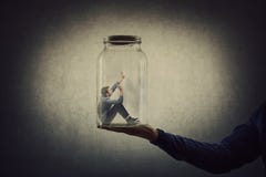 Business concept with a scared tiny man trapped inside a glass jar held by his gigantic boss hand. Surreal nightmare, helpless