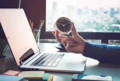 Business concepts with businessman holding clock on computer laptop.For investment analysis,Waiting to sucess stock image Business concepts with businessman holding clock on computer laptop.For investment analysis,Waiting to sucess stock image