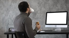 Business man in the office having breakfast, lunch and watching something on the mac, computer. White Display. royalty free stock image Business man in the office having breakfast, lunch and watching something on the mac, computer. White Display. royalty free stock image
