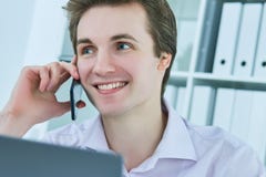 Young white collar talking to customer on mobile phone in office at workplace by laptop. Royalty Free Stock Photo Young white collar talking to customer on mobile phone in office at workplace by laptop. Royalty Free Stock Photo