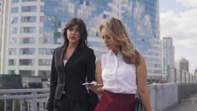 Business partners talk on the go. two business women in formal suits on the background of the business center